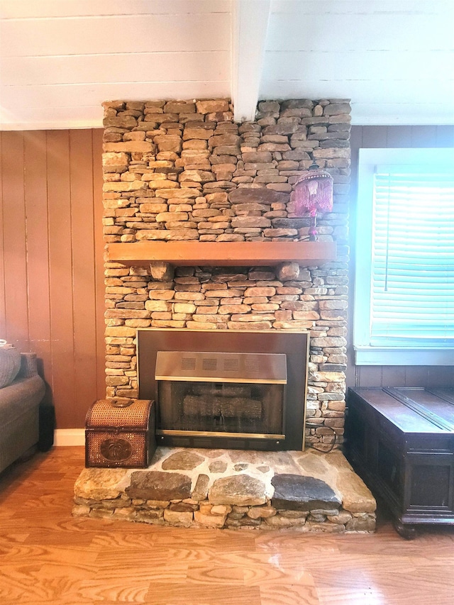 details featuring hardwood / wood-style floors, beam ceiling, a stone fireplace, and wooden walls