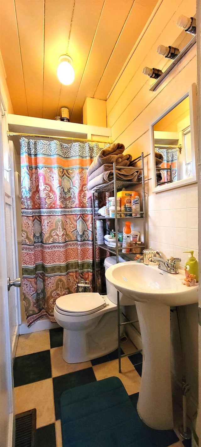 bathroom with sink, wooden walls, and toilet