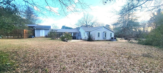 back of house featuring a lawn, central AC, and a storage shed