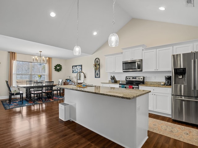 kitchen with white cabinets, appliances with stainless steel finishes, a kitchen island with sink, and backsplash