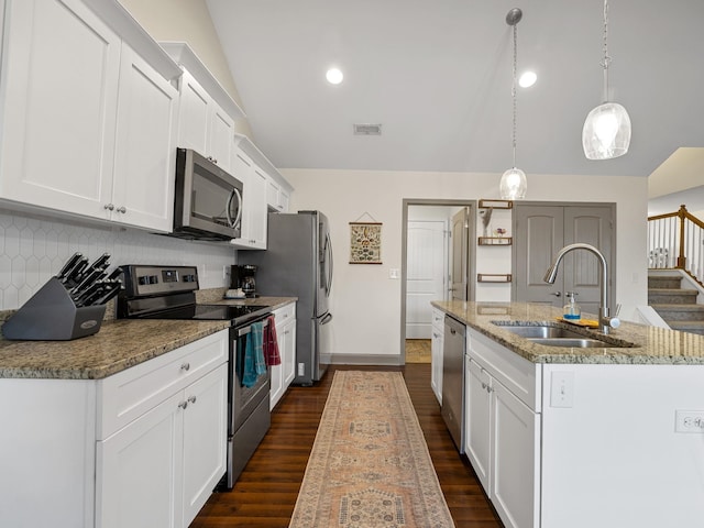 kitchen featuring sink, appliances with stainless steel finishes, white cabinetry, a kitchen island with sink, and decorative light fixtures