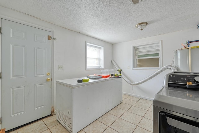 washroom with separate washer and dryer, a textured ceiling, and light tile patterned flooring