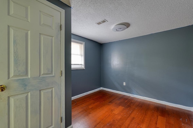 unfurnished room with hardwood / wood-style flooring and a textured ceiling