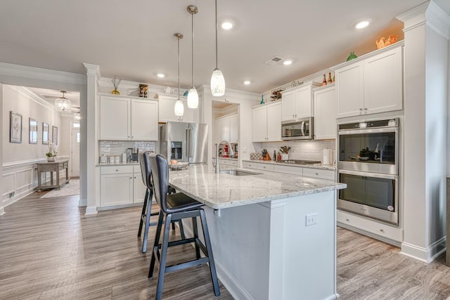 kitchen featuring a kitchen island with sink, white cabinets, and appliances with stainless steel finishes