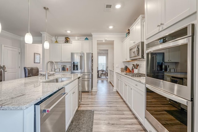 kitchen with sink, appliances with stainless steel finishes, a kitchen island with sink, hanging light fixtures, and white cabinets