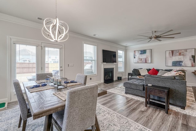 dining space featuring ceiling fan with notable chandelier, wood-type flooring, and ornamental molding