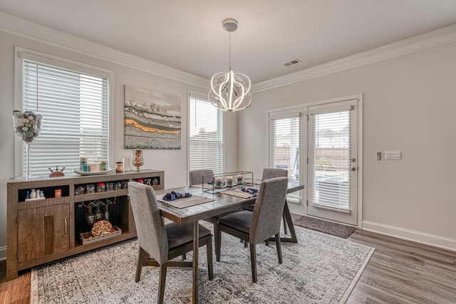 dining space with crown molding, wood-type flooring, and a chandelier