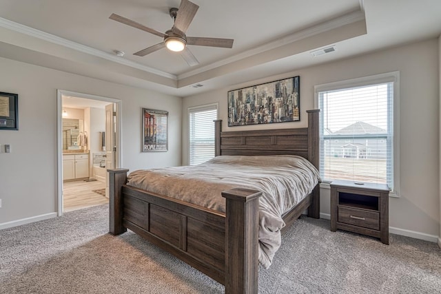 bedroom featuring ceiling fan, connected bathroom, a raised ceiling, and light carpet