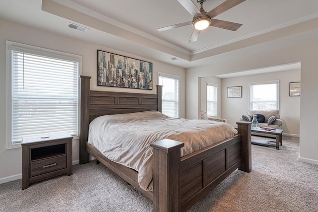 bedroom with ornamental molding, light colored carpet, ceiling fan, and a tray ceiling