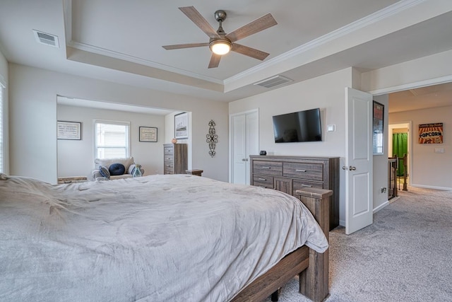 carpeted bedroom featuring a raised ceiling, ornamental molding, ceiling fan, and a closet