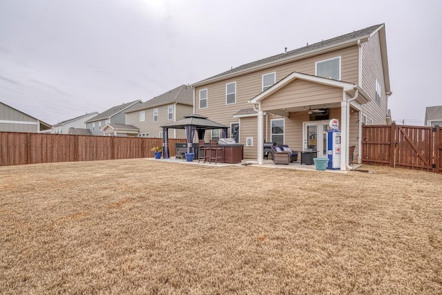 back of house with a lawn, a gazebo, a patio, a hot tub, and an outdoor hangout area