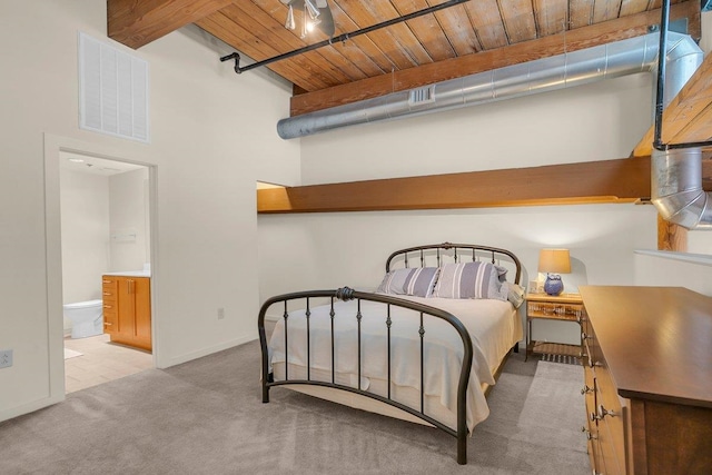 carpeted bedroom with beam ceiling, connected bathroom, wood ceiling, and a towering ceiling