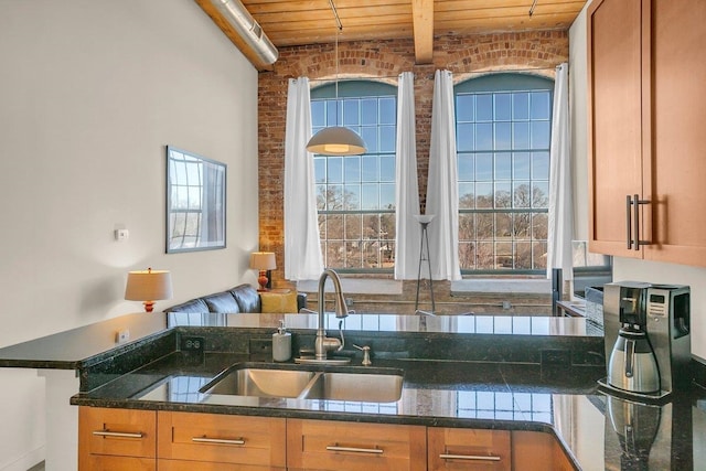 kitchen featuring sink, wood ceiling, dark stone countertops, beam ceiling, and brick wall