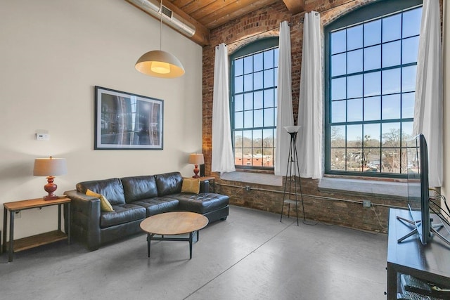 living room featuring brick wall, concrete flooring, beam ceiling, and wooden ceiling