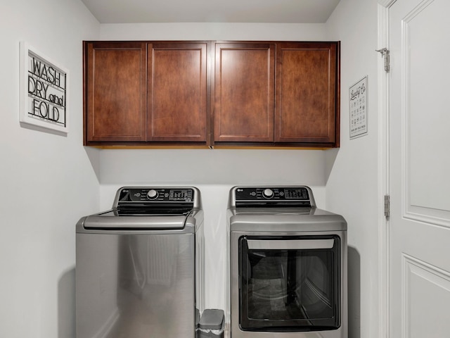 clothes washing area with washing machine and dryer and cabinets