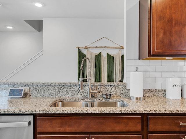 details featuring tasteful backsplash, sink, stainless steel dishwasher, and light stone counters