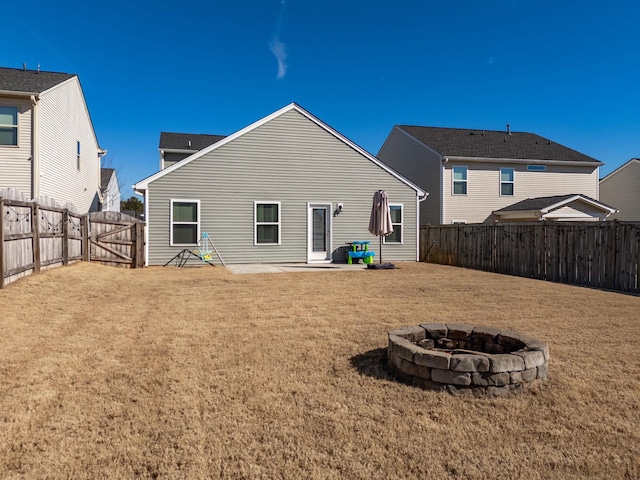 back of house featuring a patio, a lawn, and an outdoor fire pit