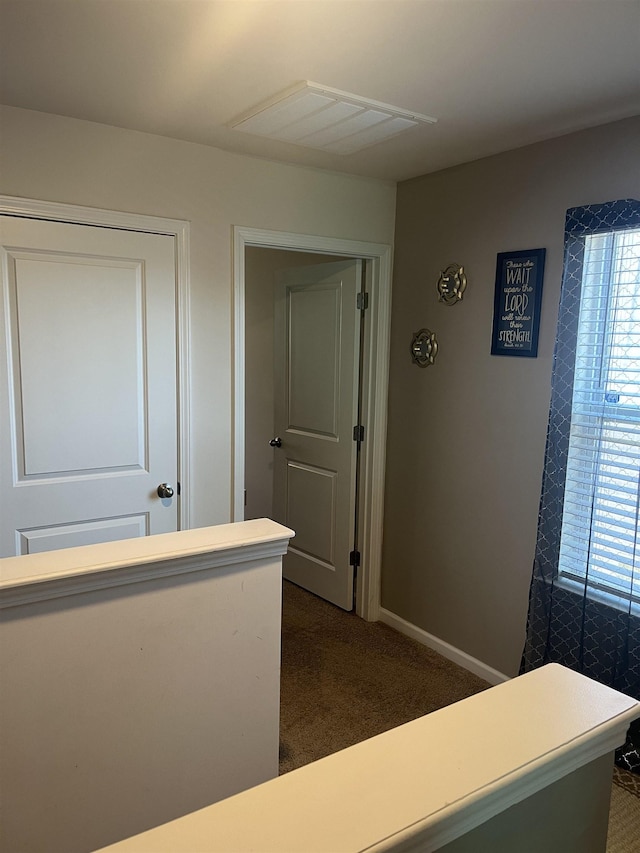 hallway with dark colored carpet