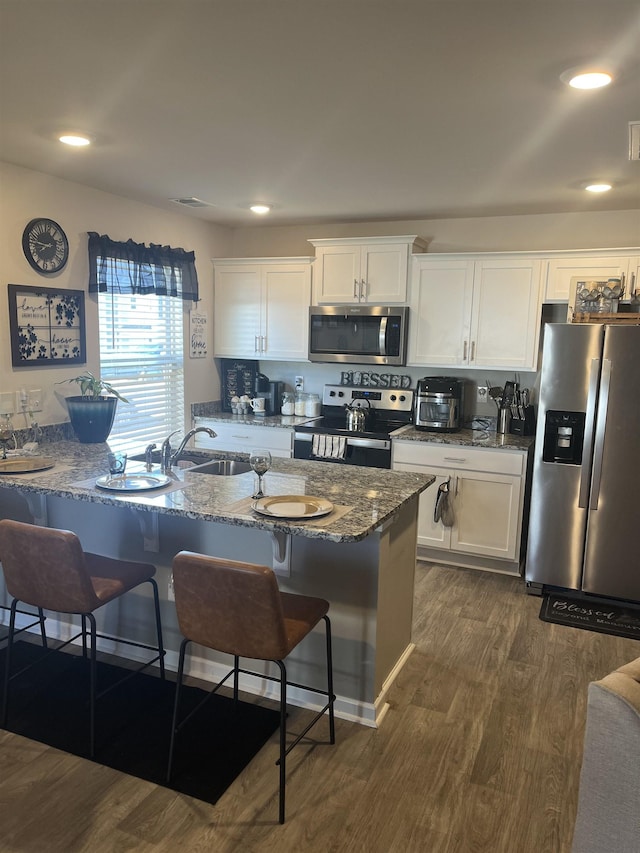 kitchen featuring white cabinetry, a breakfast bar, appliances with stainless steel finishes, and stone countertops