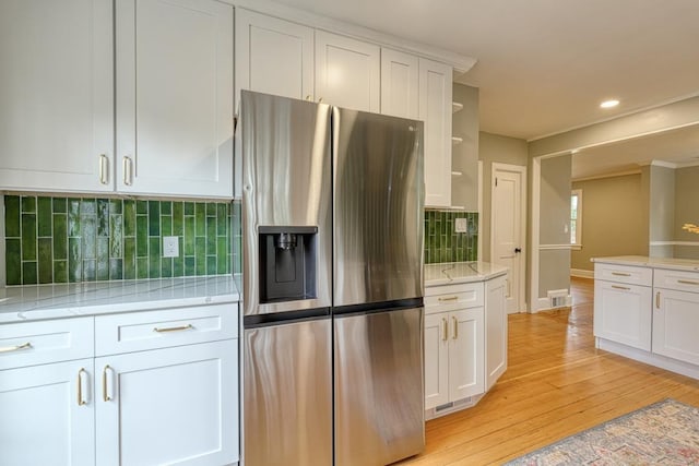 kitchen featuring light hardwood / wood-style floors, white cabinets, backsplash, and stainless steel fridge with ice dispenser