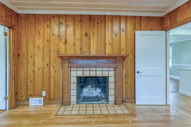 unfurnished living room featuring crown molding, light hardwood / wood-style flooring, and a tile fireplace