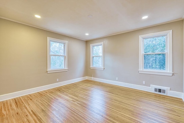 spare room featuring crown molding and light hardwood / wood-style floors