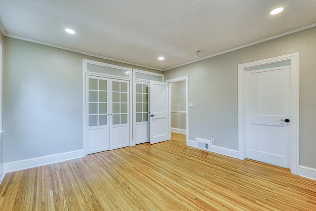 empty room with crown molding and light wood-type flooring