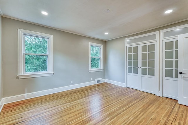 empty room with crown molding and light hardwood / wood-style flooring