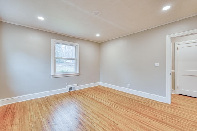 empty room with ornamental molding and light hardwood / wood-style floors