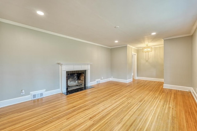 unfurnished living room with crown molding, a chandelier, a tile fireplace, and light hardwood / wood-style flooring