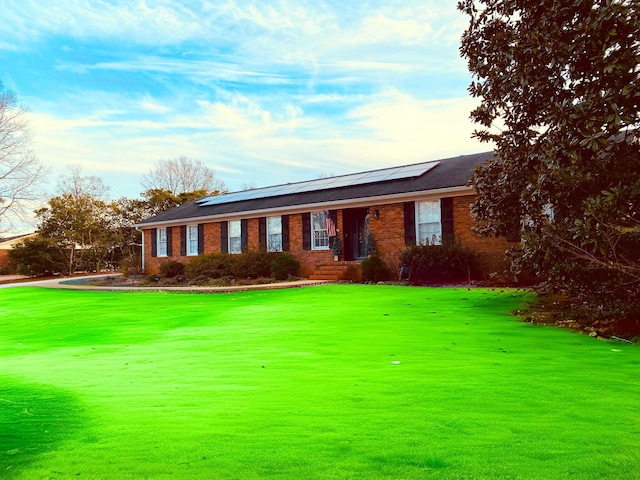 single story home with a front yard and solar panels