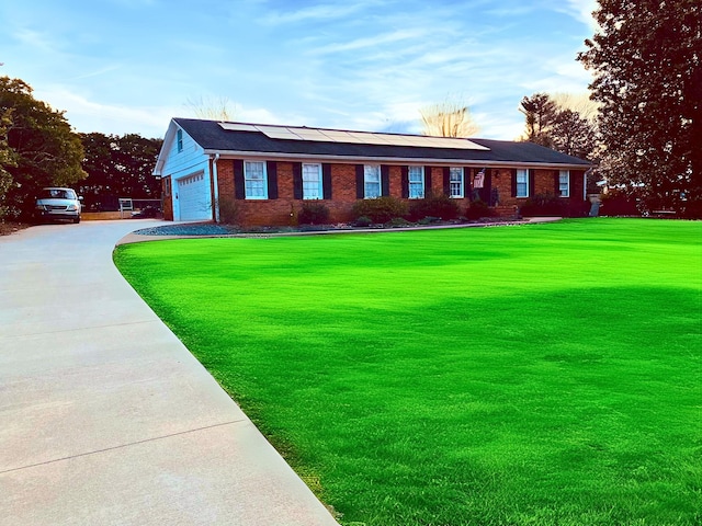 view of front of home with a garage, a front lawn, and solar panels