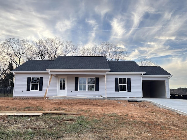 single story home with concrete driveway, covered porch, an attached garage, and roof with shingles