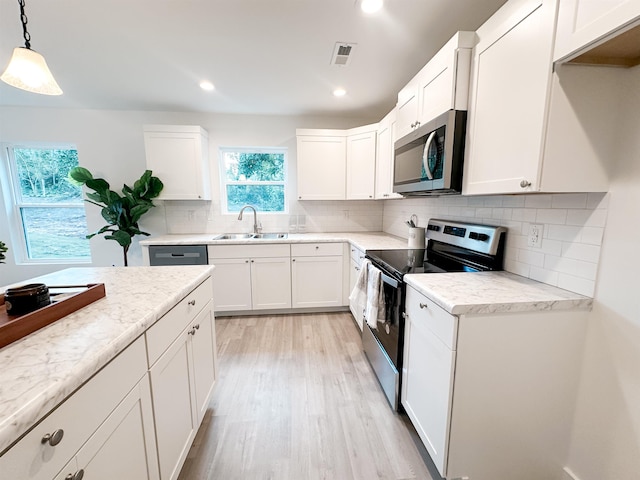 kitchen featuring stainless steel appliances, white cabinetry, sink, and pendant lighting