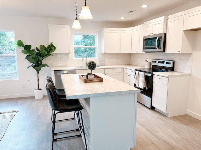 kitchen featuring sink, decorative light fixtures, stainless steel appliances, and white cabinets