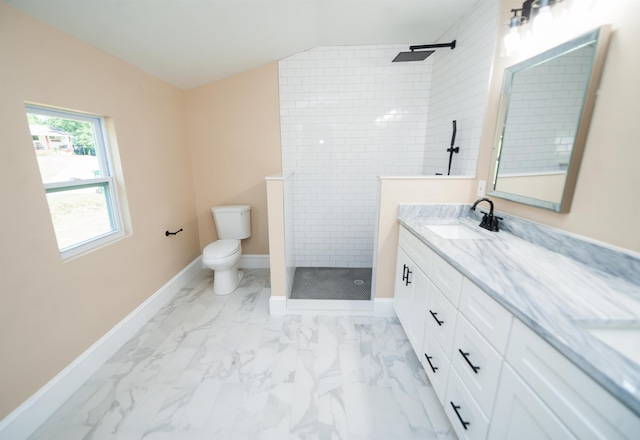 bathroom with a tile shower, vanity, vaulted ceiling, and toilet