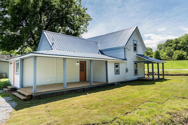 rear view of property with covered porch and a lawn