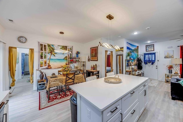 kitchen featuring pendant lighting, a center island, light hardwood / wood-style floors, and white cabinets