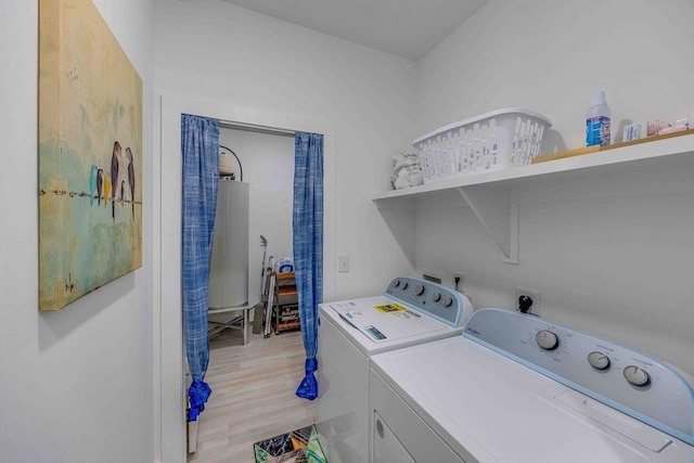 clothes washing area featuring washing machine and clothes dryer and light hardwood / wood-style floors