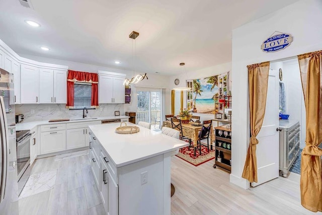 kitchen with tasteful backsplash, decorative light fixtures, a center island, stainless steel electric stove, and white cabinets