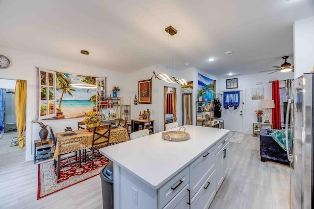 kitchen featuring pendant lighting, light hardwood / wood-style floors, stainless steel refrigerator, and a kitchen island