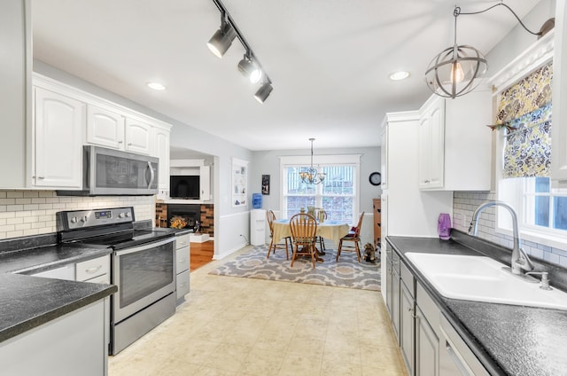 kitchen with sink, decorative light fixtures, appliances with stainless steel finishes, decorative backsplash, and white cabinets