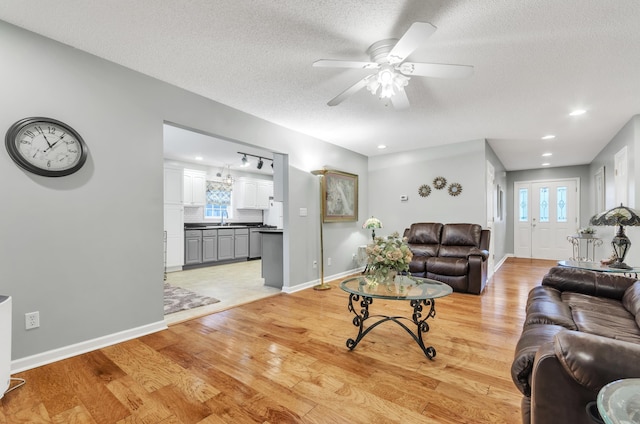 living room with sink, light hardwood / wood-style flooring, a textured ceiling, and ceiling fan