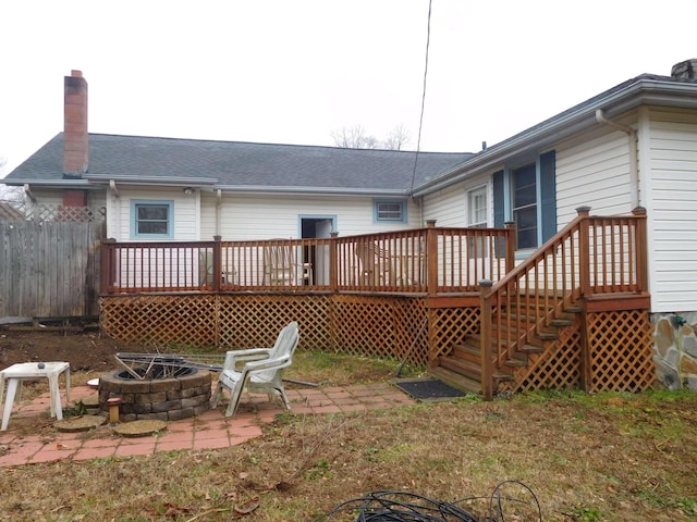 rear view of property featuring a wooden deck, a patio area, and a fire pit