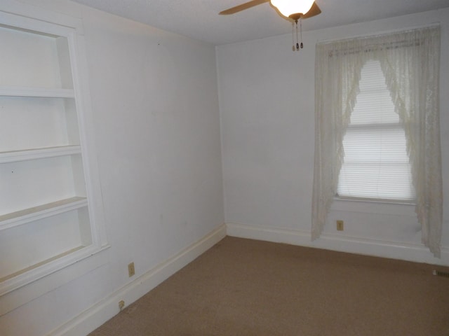 carpeted spare room with ceiling fan, plenty of natural light, and built in features