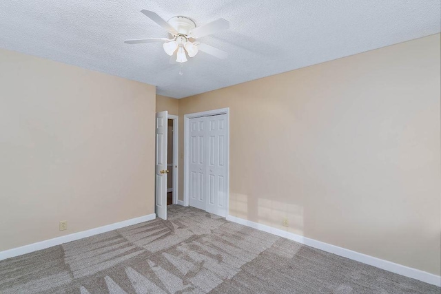 empty room with ceiling fan, light colored carpet, and a textured ceiling