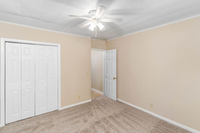 unfurnished bedroom with ornamental molding, light colored carpet, ceiling fan, and a closet