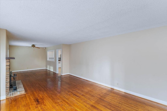 unfurnished living room featuring hardwood / wood-style flooring, ceiling fan, a fireplace, and a textured ceiling