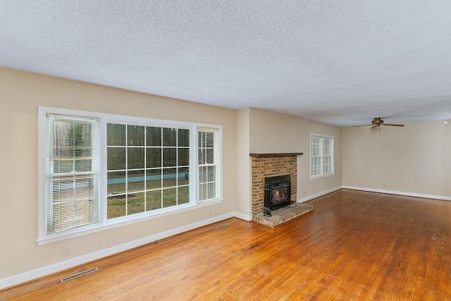 unfurnished living room featuring ceiling fan, hardwood / wood-style floors, and a textured ceiling