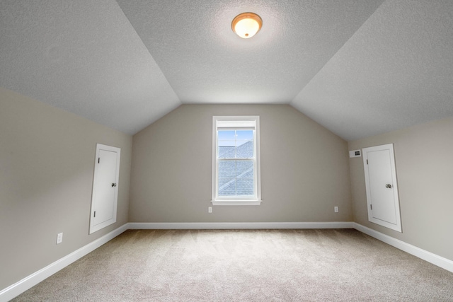 additional living space featuring lofted ceiling, carpet flooring, and a textured ceiling